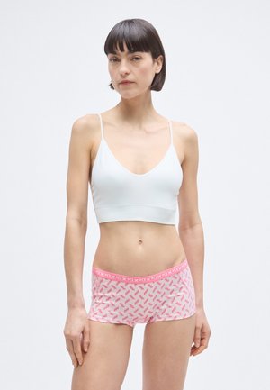 Hvit bomulls-bh med tynne stropper kombinert med rosa mønstrede boyshorts med gjentakende design og en ensfarget rosa linning.