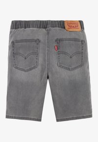 Pantalones cortos de mezclilla gris con un ajuste relajado, que cuentan con bolsillos traseros, una cintura de goma y una etiqueta de marca de cuero en la parte posterior.