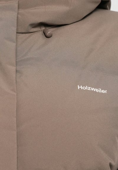 Brown outer jacket with a matte finish, featuring subtle stitching and a logo "Holzweiler" in white on the chest area.
