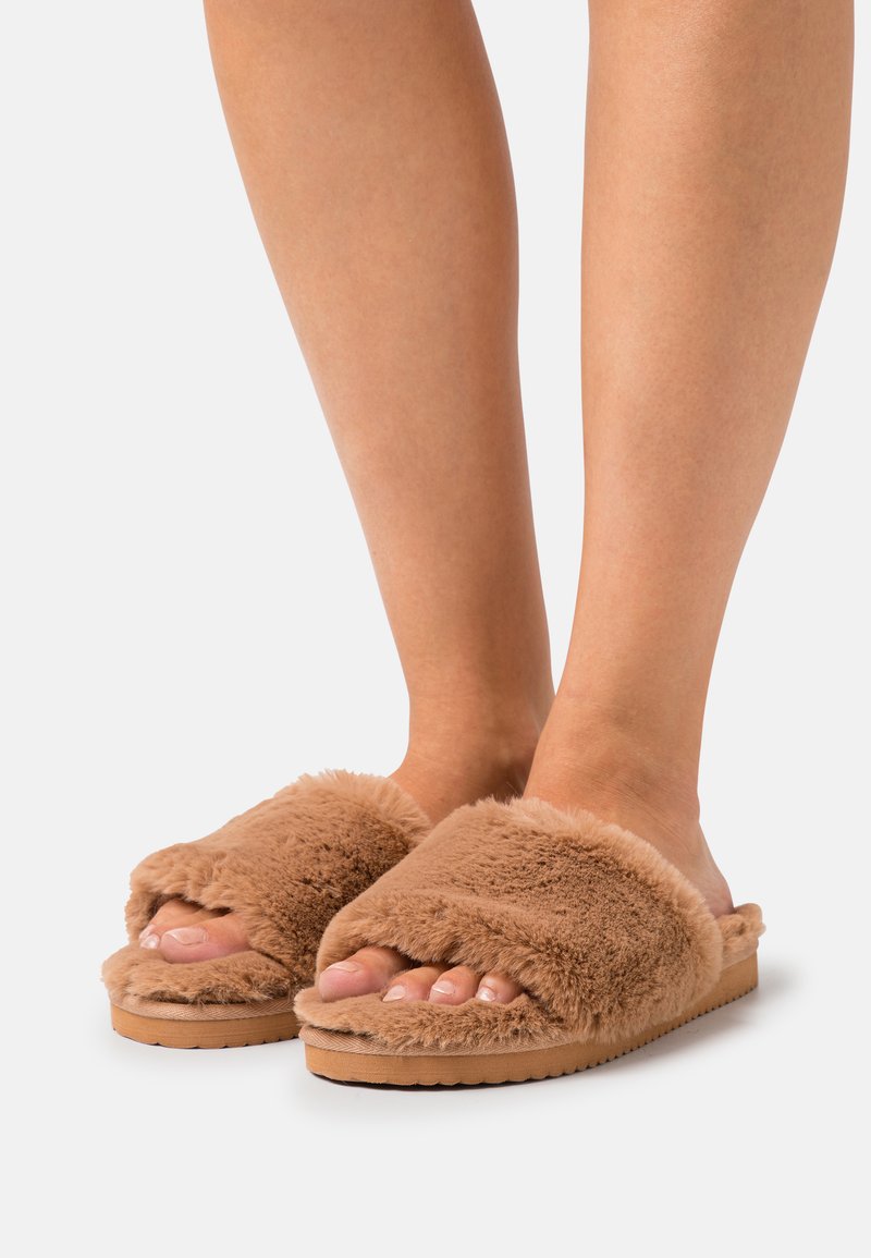 Brown faux fur slide slippers with a soft texture, wide top straps, and a flat rubber sole, designed for comfort and casual wear.