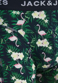 Męska bielizna z tropikalnym nadrukiem różowych flamingów i białych kwiatów na ciemnozielonym tle, z czarną elastyczną gumą w pasie.