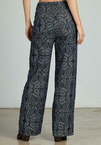 Wijdvallende broek in donkerblauw met een paisleypatroon. Heeft een smocktailleband, twee achterzakken en een gestructureerde stof.