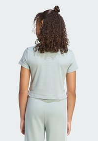 Svetlozelený krátky tričko s krátkymi rukávmi, hladkou textúrou a okrúhlym výstrihom, spárované s rovnakými svetlozelenými nohavicami.
