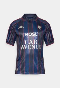 Temno modra polo majica z navpičnimi rdečimi črtami, kratkimi rokavi, ovratnikom in srebrnimi logotipi. Vsebuje tiskano sponzorsko besedilo v belem.