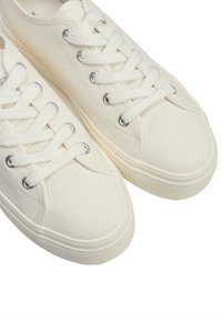 Białe płócienne trampki o gładkiej fakturze, okrągłych noskach i płaskich sznurowadłach. Posiadają metalowe oczka i lekko podniesioną gumową podeszwę.