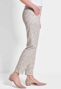 Hellbeige, gemusterte Hose mit rautenförmigem Druck, schlanker Schnitt, knöchellang, mit Seitentaschen, kombiniert mit hellbeigen, spitzen Ballerinas.