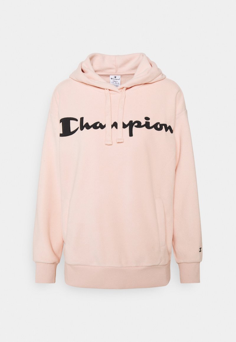 Světle růžová mikina vyrobená z měkké tkaniny, s velkým černým logem "Champion" na přední straně, se stahovacími šňůrkami a žebrovanými manžetami.
