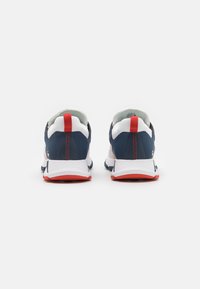 Athletic shoes in navy and white featuring a red heel tab, white midsole, and textured fabric upper with stitched accents.