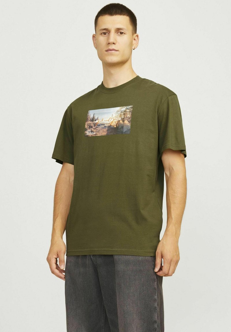 Oliven grøn bomuld T-shirt med korte ærmer og løs pasform, med et trykt grafik, der viser en naturscene på forsiden.