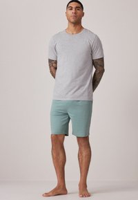 Camiseta gris de manga corta combinada con pantalones cortos de azul claro, ambos de tejido suave. El conjunto presenta un cuello redondo clásico y un corte relajado.