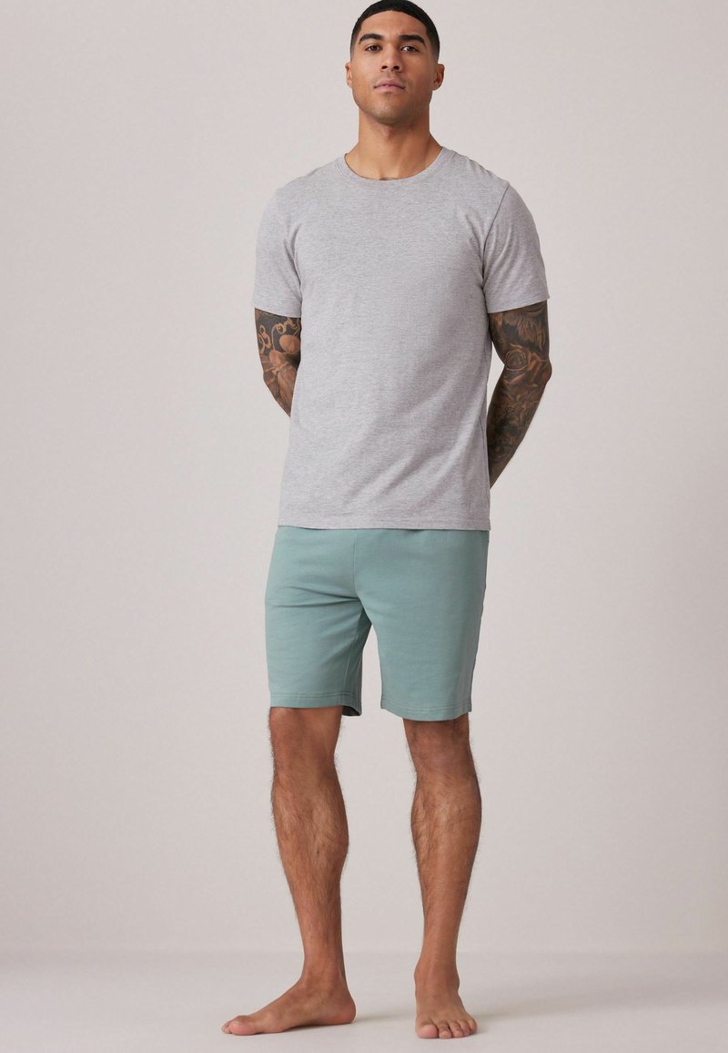 Camiseta gris de manga corta combinada con pantalones cortos de azul claro, ambos de tejido suave. El conjunto presenta un cuello redondo clásico y un corte relajado.
