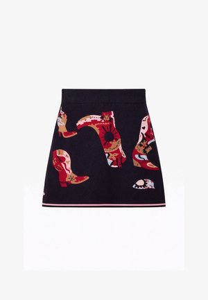 Jupe noire avec des bottes de cowboy brodées colorées et un motif de soleil, ourlet rayé rose et noir.