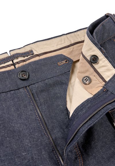 Dark denim trousers feature a tan lining with double-button closure, zipper, and contrasting stitching details.