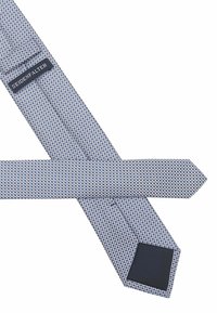 Blau-weiße gemusterte Krawatte mit einem Rautendesign. Glatte Stoffoberfläche mit einer einfarbigen dunkelblauen Rückseite. Das Etikett trägt die Aufschrift "SEIDENFALTER."