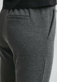 Pantalons texturés gris avec un motif subtil, dotés d'une poche latérale et d'une taille élastique pour le confort. La coupe ajustée renforce la structure.