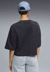 Marineblå cropped t-shirt med korte ærmer, lavet af bomuld, parret med lyseblå denim shorts. Kasketten har en lyseblå farve og justerbar ryg.