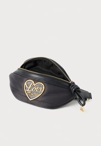 Fekete nylon övtáska szív alakú arany logóval, amelyen a "Love Moschino" felirat olvasható, cipzáros záródással és megkötött pánttal.