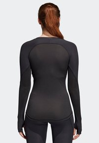 Svart långärmad träningsöverdel i elastiskt material med sömlös design och åtsittande passform, mjukt tyg och formad rygg.