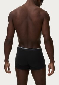Boxer shorts neri con una cintura elastica bianca, tessuto liscio, taglio aderente, design a vita bassa e silhouette elegante. Vista posteriore.