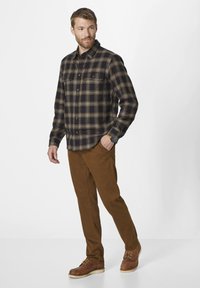 Flannel shirt in navy with yellow plaid, two chest pockets, paired with brown pants and rugged brown boots. Simple, functional design.