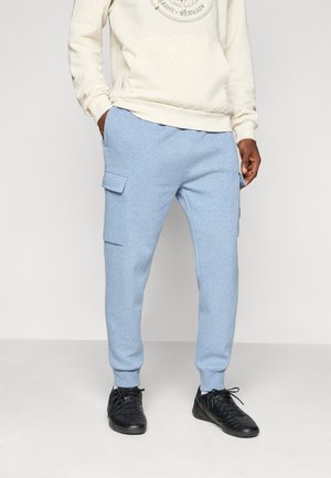 Light blue sweatpants made from soft fabric, featuring side pockets and ribbed cuffs. Paired with a cream hoodie and black sneakers.