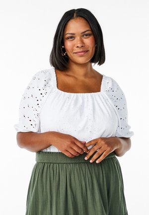 White blouse with puffed sleeves, eyelet pattern, and square neckline. Paired with a green, elastic-waist skirt. Smooth texture overall.
