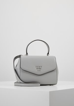 Sac à main en cuir gris DKNY New York avec poignée supérieure et bandoulière amovible posé sur une surface blanche.