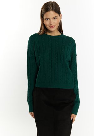 Pulover verde din tricot cu un design scurt, prezentând manșete și tiv cu nervuri, asortat cu o fustă neagră, cu o textură netedă.