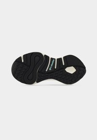 Μαύρη σόλα παπουτσιού από καουτσούκ με αυλακώσεις και υφασμένα μοτίβα. Διαθέτει λευκό ενδιάμεσο πάτο και ένα μικρό μπλε λογότυπο κοντά στη φτέρνα.