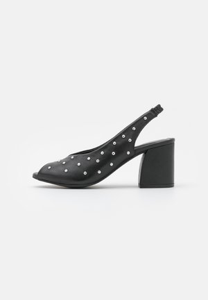 Czarny skórzany but na obcasie typu slingback z odkrytym palcem, niskim, szerokim obcasem i srebrnymi ćwiekami na cholewce i pasku.