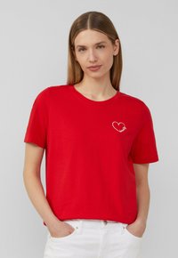 Rotes Baumwoll-T-Shirt mit kurzen Ärmeln, Rundhalsausschnitt und wei�ßem Herzmotiv mit dem Wort "Schönheit" auf der linken Brust gestickt.