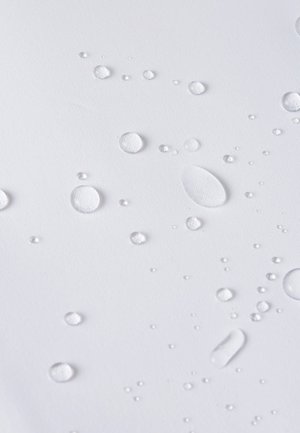 Clear water droplets on a white textured surface, varying in size and shape, with smooth, round, and oval forms reflecting light.