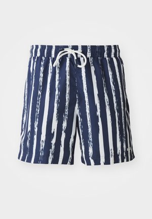 Navy swim trunks with white brushstroke stripes, elastic waistband, and white drawstring. Material appears smooth and lightweight.