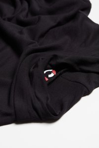 Czarna tkanina o gładkiej fakturze, z małym logo w czerwono-białych kolorach na krawędzi. Materiał wydaje się lekki i miękko się układa.