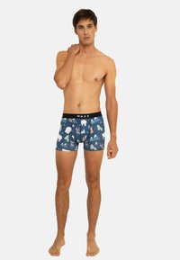 Boxer-briefs pour hommes à motifs en bleu foncé avec des designs d'ours, de cerfs et d'arbres ; ceinture élastique noire avec le logo "WAXX" ; en coton.