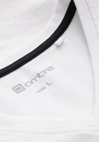 Maglietta in cotone bianco con scollatura rotonda e bordo nero, con etichetta del marchio "ombre" e taglia "L" in grigio.