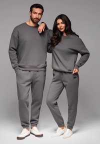 Sudaderas y pantalones de chándal a juego en gris para hombres y mujeres, con puños acanalados, corte relajado y detalle del logo en los dobladillos.