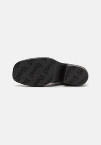Black rubber shoe sole featuring embossed "CAMPER" logo, a flat design with a curved heel section, textured surface, and size indicator.