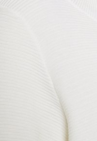 Biała dzianina prążkowana o miękkiej teksturze, ukazująca zbliżenie linii materiału i subtelnego połysku.