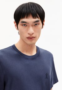 Navyblauwe katoenen t-shirt met een ronde hals, korte mouwen en een klein logo op de linkerkant van de borst. Zachte textuur en een comfortabele pasvorm.