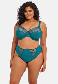 Teal-lingkaran lingerie set yang terdiri dari bra dan celana dalam model tinggi. Bra tersebut dihiasi dengan aksen renda bunga dan detail pita di tengah. Tekstur kain yang halus.