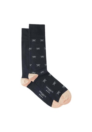 Chaussettes bleu foncé avec un motif de nœud papillon blanc répété, dotées de doux accents roses au niveau des orteils et d'un détail de logo près de la cheville.