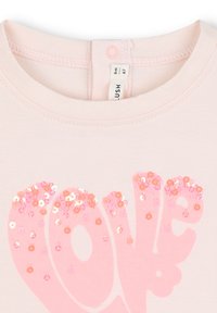 T-shirt rosa chiaro con maniche corte, caratterizzata da una grande grafica "love" decorata con paillettes rosa e arancioni. Tessuto in cotone morbido.