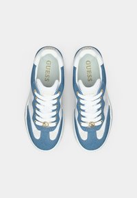 Μπλε αθλητικά παπούτσια από τζιν με λευκές λεπτομέρειες, χρυσά μεταλλικά στοιχεία, στρογγυλή μύτη και σκοινάκια για δέσιμο. Φέρουν λογότυπο στη γλώσσα και στη πλευρά.