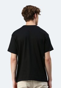 T-shirt in cotone nero con scollatura rotonda, maniche corte e vestibilità comoda, caratterizzato da una texture liscia senza elementi decorativi visibili.