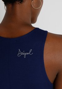 Granatowy top bez rękawów z okrągłym dekoltem i haftowanym logo "Desigual" na plecach. Miękki materiał o gładkiej fakturze.