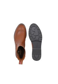 Brązowy skórzany botek za kostkę z detalami w stylu brogue, elastycznym bocznym panelem i pętelką do zakupu. Czarna gumowa podeszwa z wzorem bieżnika w kształcie serca.