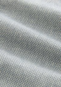 Tissu texturé de couleur bleu clair avec un motif de tissage fin. La surface est lisse avec des variations subtiles d'ombre et de détails de fil.