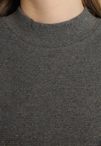Grau gestreifter Pullover mit hohem Kragen, der goldene Sprenkel im gesamten Stoff aufweist. Der Stoff wirkt weich und dehnbar.