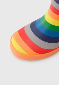 Λαστιχένια μπότα με μοτίβο ουράνιου τόξου και στρώσεις ζωντανών χρωμάτων (κόκκινο, πορτοκαλί, κίτρινο, πράσινο, μπλε, μωβ) με πορτοκαλί υφή στη σόλα.